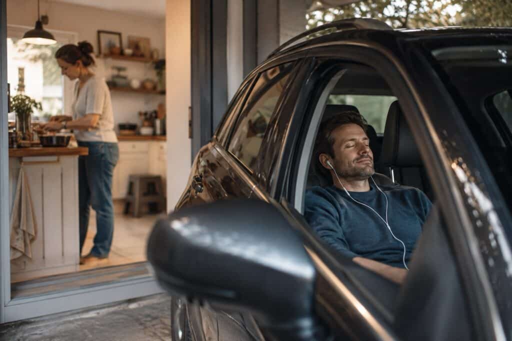 Schweigen nach dem Streit – sie in der Küche, er allein im Auto mit Kopfhörern und geschlossenen Augen.